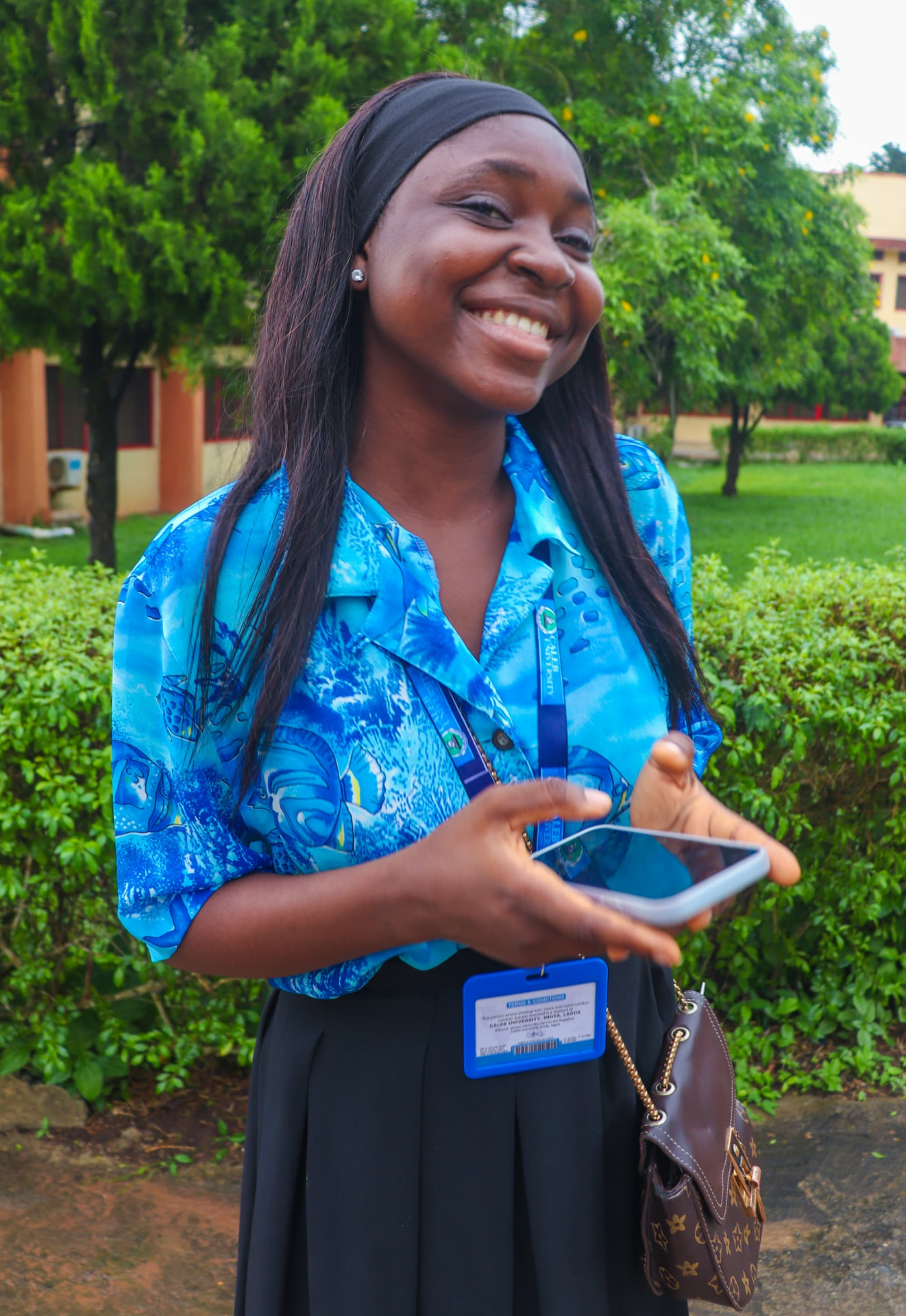 Smiling Caleb University student holding her phone on campus