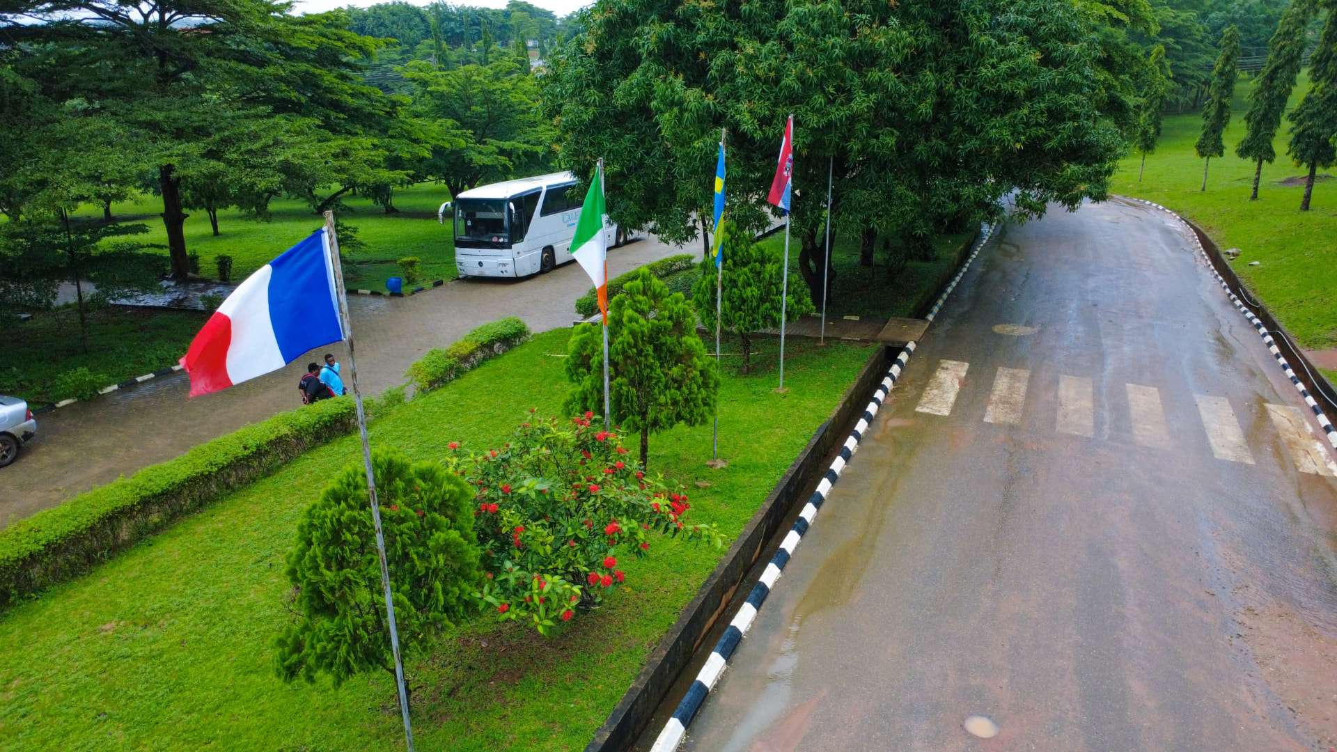 Campus gardens with international flags and university bus